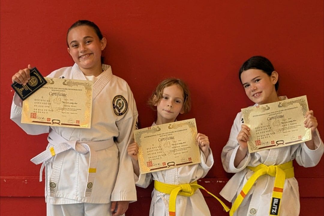 Three of our young members smiling with their new grade certificates.
